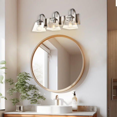 3 Light Modern Brushed Nickel Vanity Light Over Mirror Industrial Wall Sconce With Clear Glass Shades in a bathroom setting.