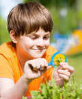 Child using a blue 5 inch magnifying glass from the Colorful 48 Pack 5 Inch Kids Magnifying Glass Set for outdoor exploration.