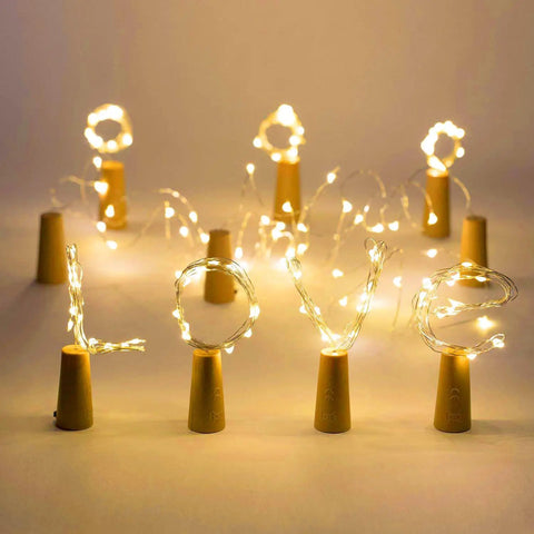 Wine Bottle Cork Lights With 12 LED Fairy String Lights Waterproof Battery Operated 10 Pack arranged to spell 'LOVE' in warm white.