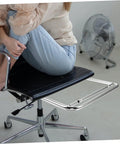 Robust Stainless Steel Retractable Office Chair Footrest Smooth Flip Down Leg Rest Solid Leg and Knee Support Pro Grade Desk Grind Setup Fast Lift Out Platform with a user seated, showing the black seat and stainless steel footrest.