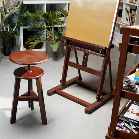Wooden Drafting Stool With Adjustable Height For Artists Studio And Home Workspace next to an easel, German Beech Wood Craft Chair