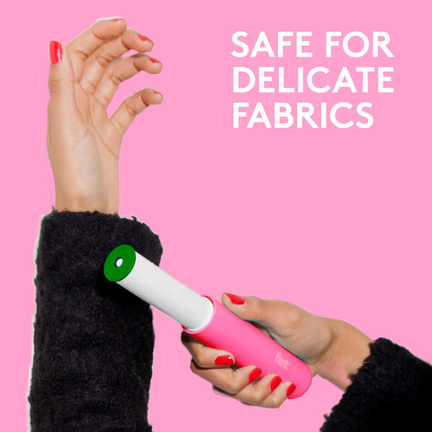 Using pink retractable mini lint roller with 30 extra sticky sheets on sweater, highlighting easy twist mechanism.