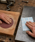 Hands using Heavy Duty Aluminum Oxide Sandpaper for Waterproof Projects on wood and metal surfaces.
