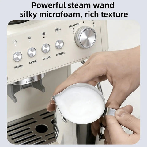 Close-up of a hand frothing milk with a steam wand on a 15 Bar Espresso Machine With Built-In Anti-Clog Grinder And Milk Frother Steam Wand Tamping Tools For Lattes And Cappuccinos Fast Eject Ground System Home Barista Grade Coffee Maker In Almond Finish