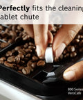 Hand placing VeroCafe Espresso Cleaning Tablet into coffee machine chute with coffee beans visible