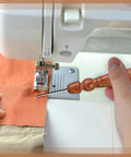 Using Go-To Stiletto and Pressing Tool for Quilting and Sewing with stainless steel tip, guiding fabric through sewing machine.
