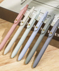 Pack Of Six Smooth Writing Retractable Gel Pens Featuring Snappy Click Mechanism And Fast Drying Black Ink That Rolls Dead Smooth Across Pages Ideal For Classroom Assignments Desk Organization And Daily Note Taking Without Any Smudging on a wooden table.