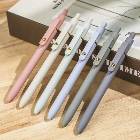 Pack Of Six Smooth Writing Retractable Gel Pens Featuring Snappy Click Mechanism And Fast Drying Black Ink That Rolls Dead Smooth Across Pages Ideal For Classroom Assignments Desk Organization And Daily Note Taking Without Any Smudging on a wooden table.
