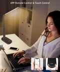 Smart LED Desk Lamp With Eye Caring Light, Stepless Dimming And Timer, in a home office setup with a laptop and phone.