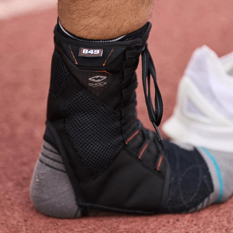 Close-up of 849 Ultra Gel Lace Up Ankle Support with Internal Gel Cushions for all day comfort, large black on athlete's foot.