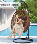 Egg Chair With Stand For Indoor And Outdoor Relaxation by pool, brown wicker, thick cushion, girl seated, tropical background.