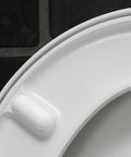 Close-up of the Slick Starck 3 White Toilet Seat with smooth finish and soft close hinge feature on a dark background.
