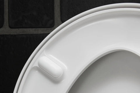 Close-up of the Slick Starck 3 White Toilet Seat with smooth finish and soft close hinge feature on a dark background.