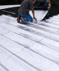 Two workers applying Heavy Duty Self Adhesive Roofing Tape For Fixing Shingles And RV Leaks on a roof surface for waterproofing.