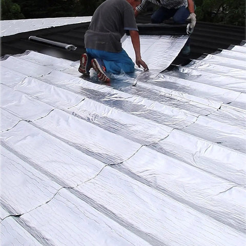 Two workers applying Heavy Duty Self Adhesive Roofing Tape For Fixing Shingles And RV Leaks on a roof surface for waterproofing.