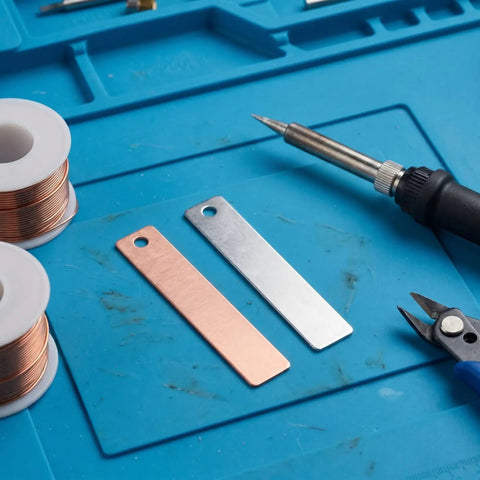 Copper Zinc Electroplating Kit 20 Pieces Metal Sheets 1.57x0.35x0.08 Inches on blue mat with tools for DIY projects