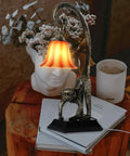 Gold Finish Resin Monkey Table Lamp on a desk, featuring a cool modern design with a curved tail, beside books and a plant.