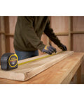 Man using Tape Measure With Blade Armor Built Tough 8 M Metric, Shock Resistant, Mylar Coating, Cushion Grip, Wide 32mm Blade, 3.35 M Standout, Class II Accuracy, Model 0-33-728 on wooden plank