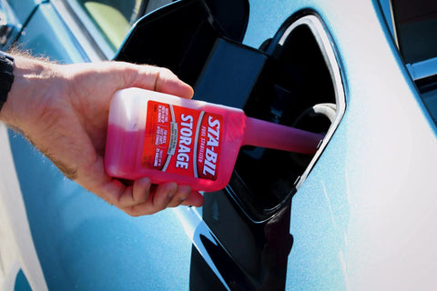 Storage Fuel Stabilizer For Long Term Fuel Freshness And Engine Protection Keeps Gasoline Fresh Up To 24 Months Treats 25 Gallons 10 Fl Oz being poured into a car's fuel tank
