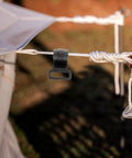 Close-up of a large plastic camping tent hook attached to a rope, highlighting its sturdy design for hanging outdoor gear.