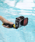 Person holding GoPro Hero Waterproof Housing With Floating Hand Grip For Depth Up To 196ft, red filter visible, in pool water
