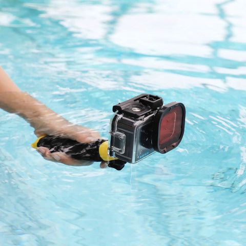 Person holding GoPro Hero Waterproof Housing With Floating Hand Grip For Depth Up To 196ft, red filter visible, in pool water