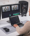 Person editing video on computer with Wireless Pro Compact Wireless Microphone System and smart charge case on desk.