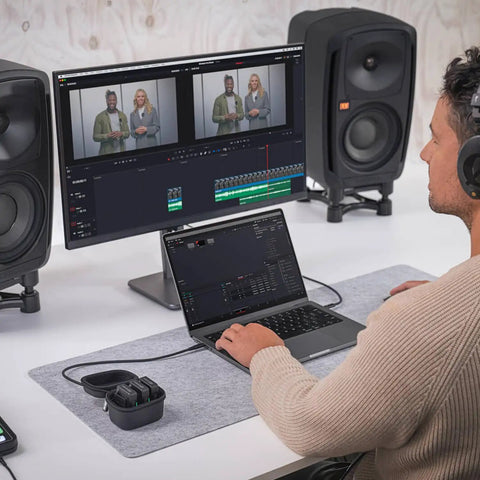 Person editing video on computer with Wireless Pro Compact Wireless Microphone System and smart charge case on desk.