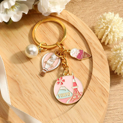 Tokyo Travel Keychain With Hot Air Balloon Ice Cream And Pearl Charms For Keys Cute Souvenir For Women Mt Fuji Silhouette Engraved Design Perfect Travel Keepsake For Japan Trips, displayed on a wooden surface.