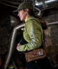 Person wearing Legacy Womens Essentials Convertible Crossbody Bag And Waist Pouch in rustic setting.