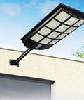 JUDYSSY Solar Street Lights Outdoor Remote Control mounted on wall, showing sleek design and bright LEDs.