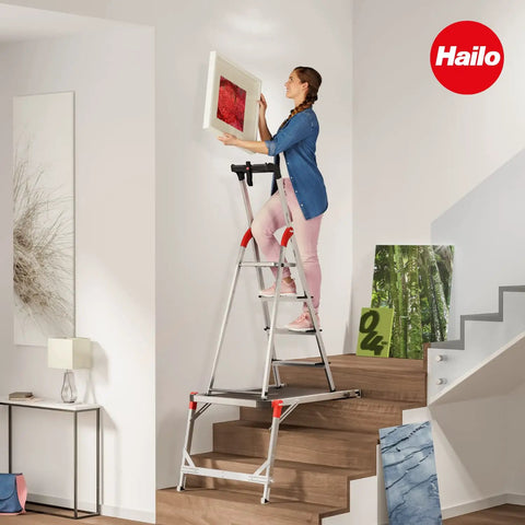 Woman using Aluminum Staircase Platform With Height Adjustable Telescopic Rails And Feet Built In Bubble Level Two Hand Safety Release Non Slip Base With Soft Grip Feet Rock Solid Stability For Use With Step Stools And Stepladders on stairs.