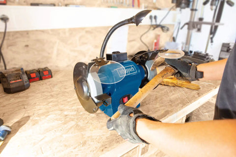 Heavy Duty Double Bench Grinder Boasts A Rock Solid 550 Watt Induction Motor For Noise Free Grindin Work With Adjustable Spark Guard and flex work lamp in use.