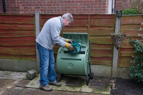 Person using Back Porch Compost Tumbler For Small Yards And Urban Spaces With Odor Control And Fully Enclosed Design That Keeps Animals Out
