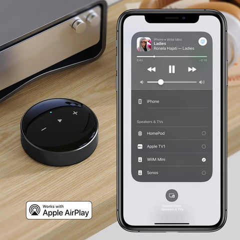AirPlay 2 Wireless Audio Streamer for Multiroom Stereo and TV Audio Preamplifier Turns Your Home Stereo Into a Smart Speaker Works With Alexa and Siri Streams Hi Res From Amazon Music Tidal and More next to smartphone showing audio streaming interface