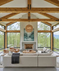 Spacious living room with wooden beams, large windows, warm oak accents, and a cozy sectional sofa.