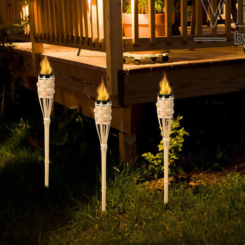 Natural Bamboo Tiki Torch Outdoor Set 2 Pack With Decorative Woven Design For Backyard Vibes And Garden Lighting Outdoor Parties Weddings Festivals Eco Friendly Oil Lamps installed in a garden