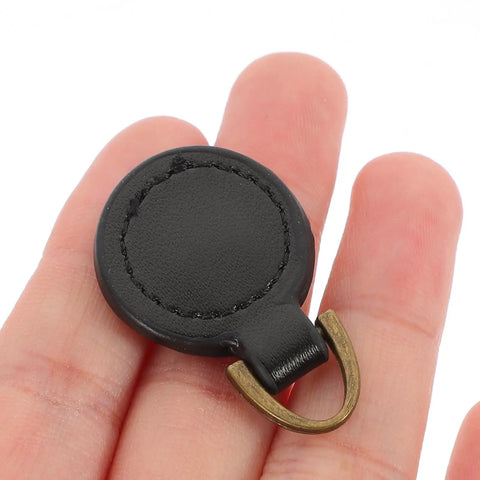 Five Piece Set Of Badass Black Alloy Zipper Pull Replacement Tabs For Heavy Duty Backpacks on a hand, showcasing black alloy material.