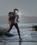 Hiker wearing Beast Mode Bright 1000LM LED Headlamp Flashlight 4 Pack With 230 Degree Wide Beam, crossing rocky shoreline.