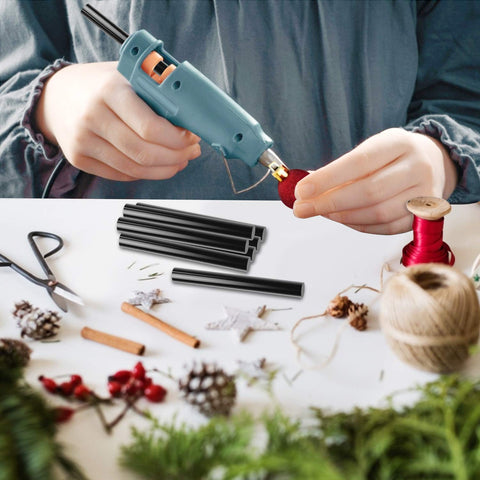 Person using hot glue gun with Clear Hot Glue Sticks 36 Pack Bulk Full Size 3.93 Inch By 0.43 Inch for DIY crafts on a table