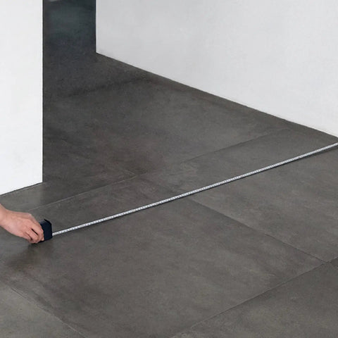 Using Self Locking Tape Measure Pocket Size Retractable Dual Unit Feet Meters Gadget on gray tiled floor