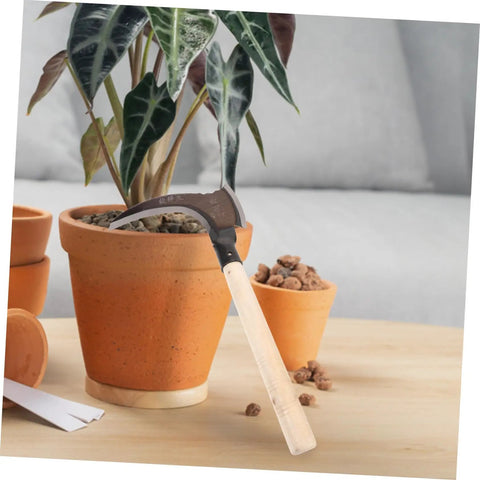 Do-It-All Manganese Sickle Garden Tool With Detachable Handle leaning against a potted plant, showcasing the sturdy blade and wooden handle.