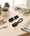 50 Pack No Tie Shoe Lace Clips With Paracord End Caps And Zipper Pulls, Versatile Paracord Tips For Drawstrings, Backpacks, And Running Shoes, Black, Ideal For Athletes. Black lace clip and paracord end cap shown on wooden table.