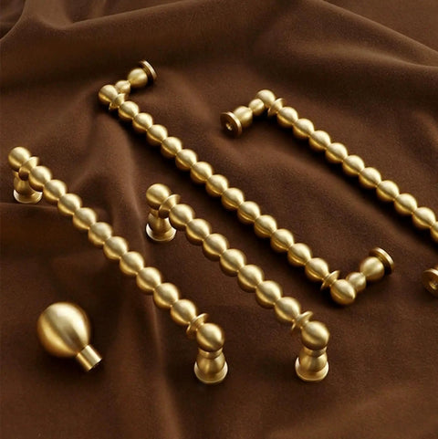 Bead Cabinet Pulls in Brushed Brass With Ball Knobs, displayed on a fabric background, showing vintage modern drawer handles.