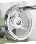 Close-up of carbon steel crank handle handwheel for lathe, revolving knob edge, installed on green machine tool