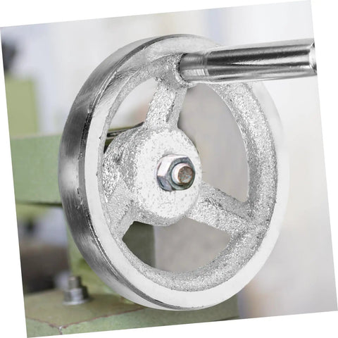 Close-up of carbon steel crank handle handwheel for lathe, revolving knob edge, installed on green machine tool