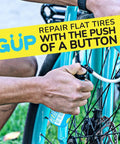 Person using Quick Fix Tire Sealant And Inflator 2 Pack For Tubeless And Tubed Tires on blue bicycle with Schrader valve adapter.