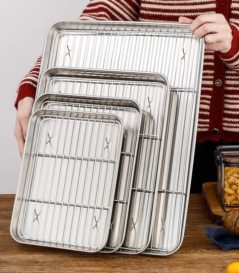 Person holding a set of Small Stainless Steel Serving Trays With Cooling Wire Racks Set 304 Grade, various sizes, shiny finish.