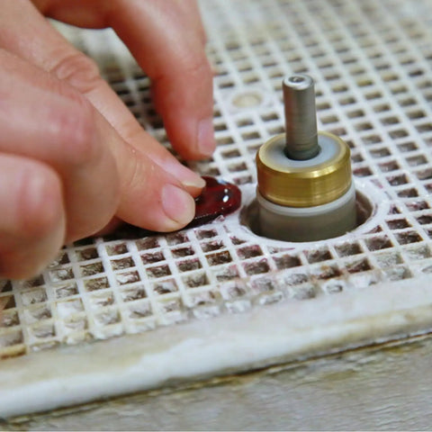Person using Stained Glass Diamond Grinder Bit Set Pro Grade 4 Size Heads For Glass Drilling Brass Core Bits to shape a red gem
