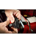 Powerbuilt universal thread repair tool, black, for SAE 5/32–3/4 in and metric 4–19 mm, shown in hand near a vise.
